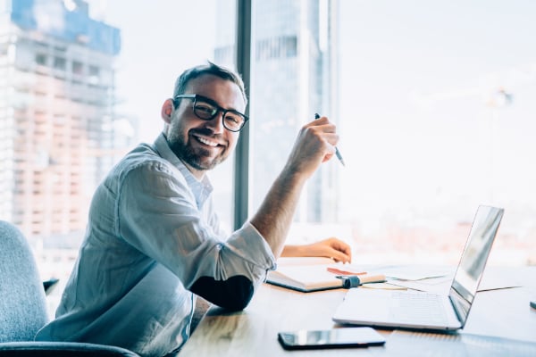 336552733-friendly-man-sitting-at-office-desk-600px